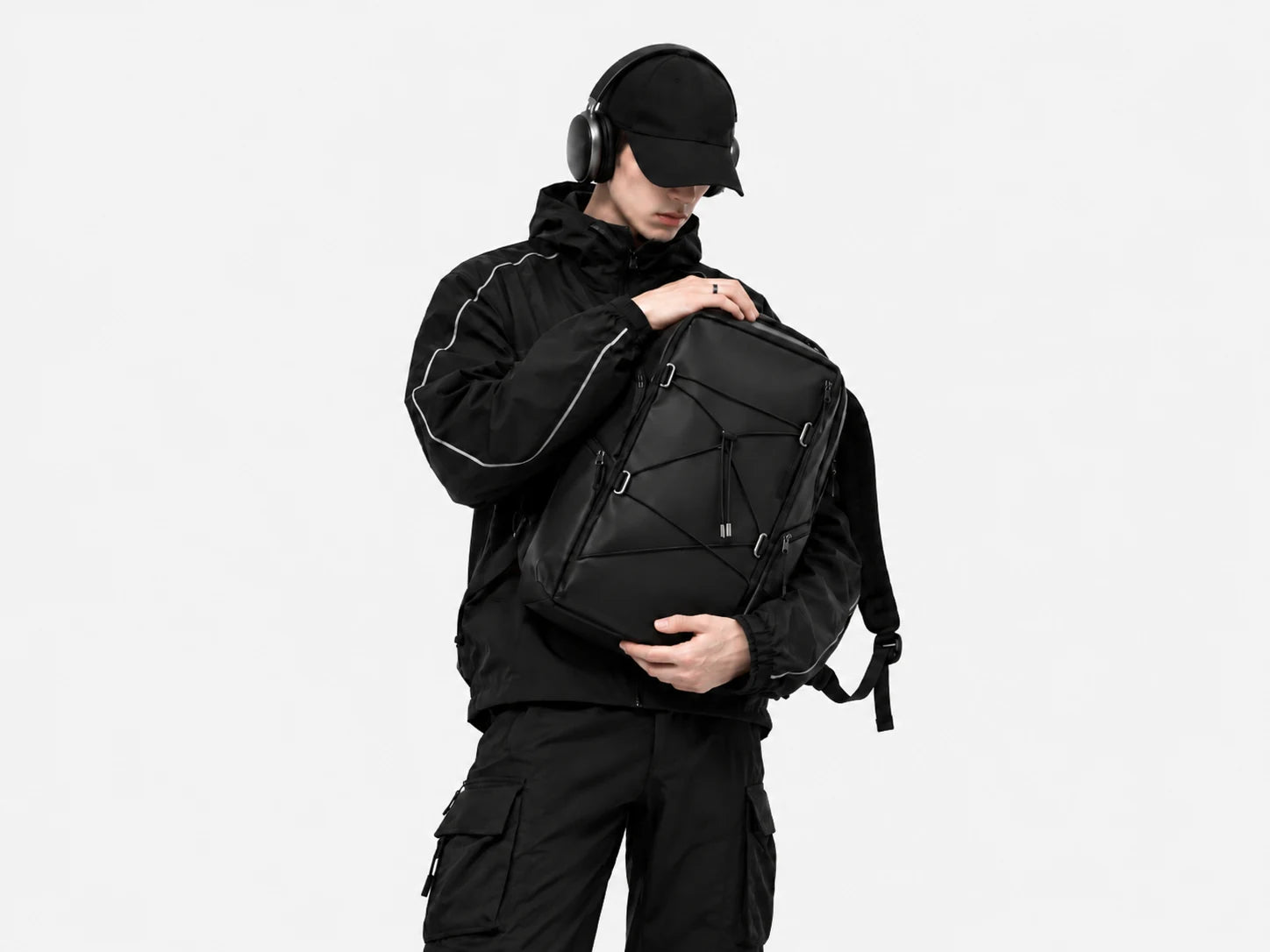 Model wearing headphones and holding a black backpack